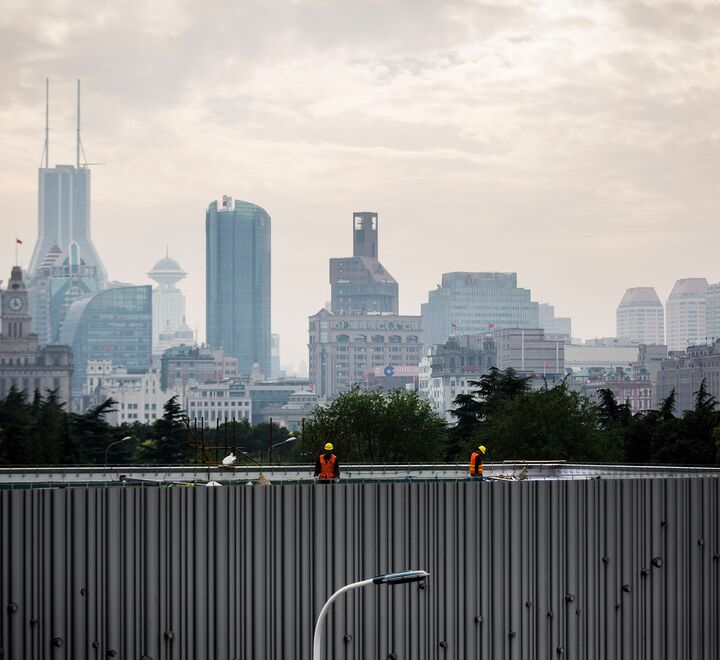 Arbeidere på en bro med høye bygninger i bakgrunnen